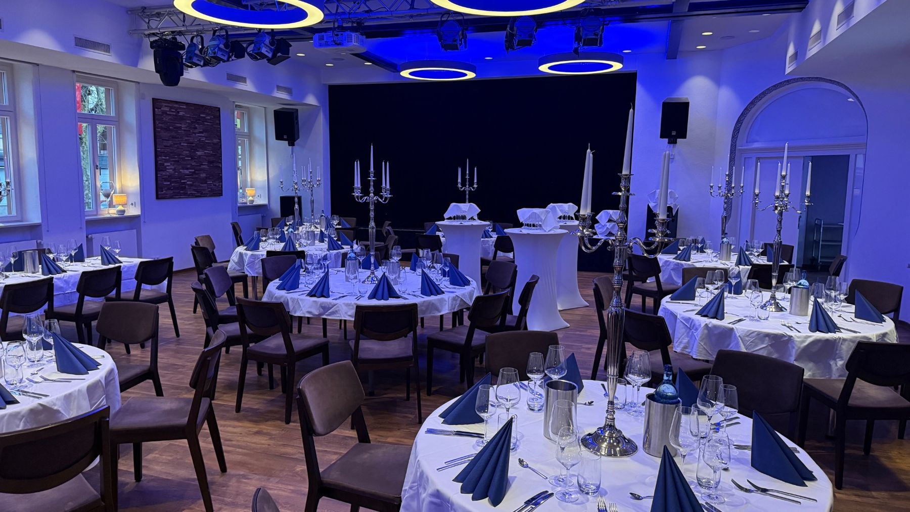 Saal mit runden Tischen in blauem Licht