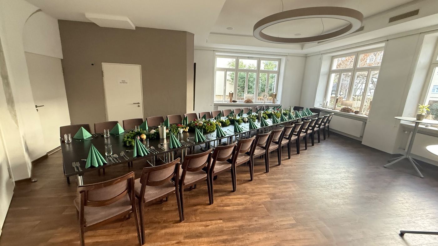 Lange Tafeln mit grünen Servietten im hellen Saal
